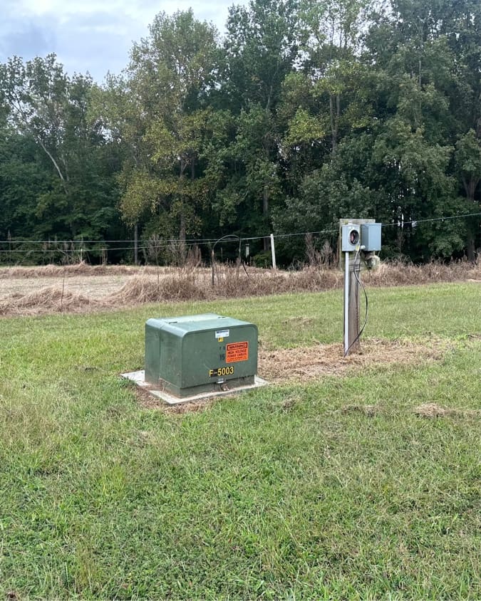 Field cut back around a utility pedestal, with the uncut brush line still standing behind it